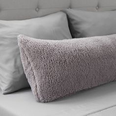 a close up of a bed with pillows and blankets on it's headboard