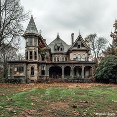 an old victorian style house in the middle of a field with leaves on the ground