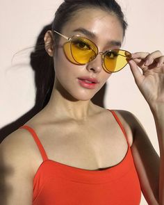 a woman in an orange top and yellow sunglasses