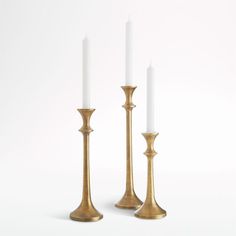 two brass candlesticks with one white candle