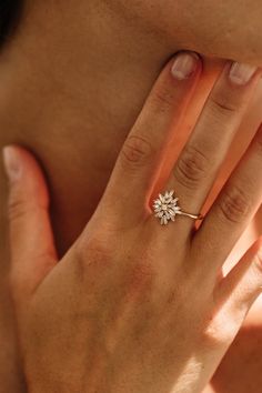 a woman's hand with a diamond ring on her left hand and the other hand holding it up to her face