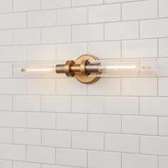 a bathroom light that is on the side of a wall with white bricks behind it