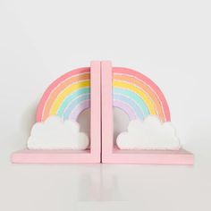 a pink bookend with a rainbow and clouds on it's sides in front of a white background