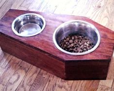 a wooden box with two metal bowls on the top and one is filled with dog food