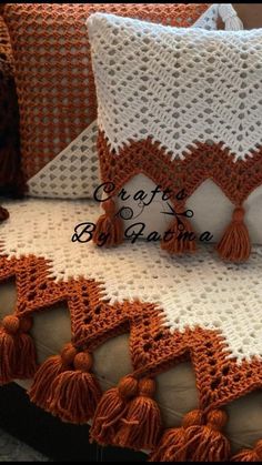 a crocheted pillow with tassels on it sitting on top of a couch