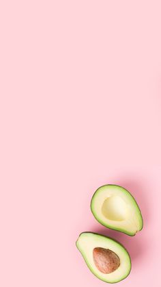 an avocado cut in half on a pink background