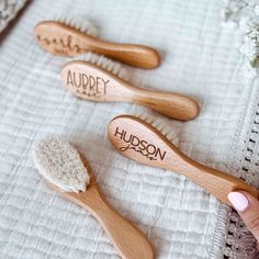 three personalized wooden toothbrushes with names on them sitting on a white towel