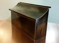 a shiny metal box sitting on top of a wooden table next to a white wall