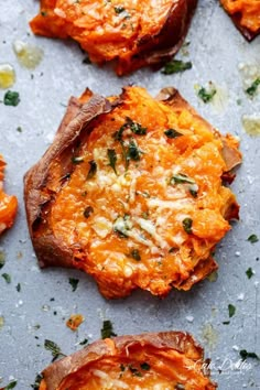 three pieces of bread with cheese and herbs on top, sitting on a table next to other food items