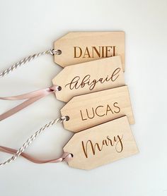 three wooden tags with names on them are hanging from string and tied to the wall