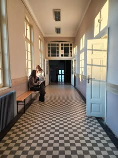 a woman sitting on a bench in an empty hallway