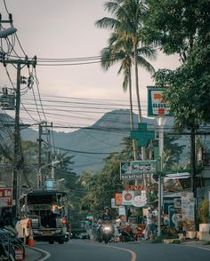 a city street filled with lots of traffic and palm trees on the side of it