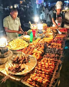 several people standing around a table filled with food