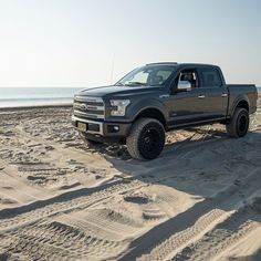 a black truck is parked on the beach