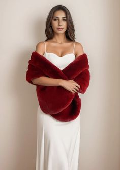 a woman in a white dress is wearing a red fur shawl with her hands on her hips