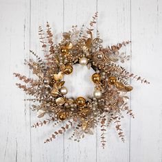 a wreath with gold ornaments hanging on a white wall