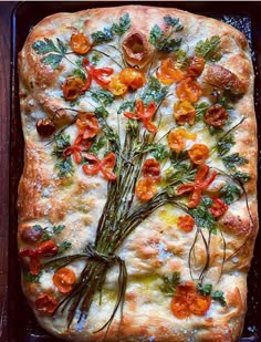 a square pizza with tomatoes and asparagus on it in a baking pan, ready to be eaten