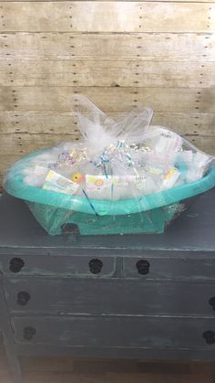 a basket filled with baby items sitting on top of a wooden dresser next to a wall