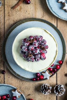 a cake with white frosting and cranberries on top, surrounded by christmas decorations