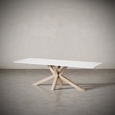 a white table sitting on top of a cement floor next to a wall with a wooden cross leg