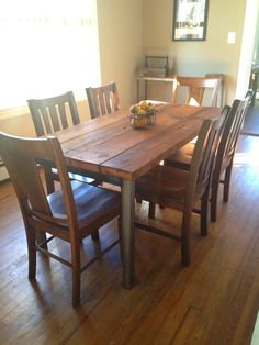 a wooden table with chairs around it on a hard wood flooring area in front of a window