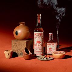 an assortment of items including a bottle, mortars and bowl on a red surface