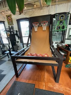 an indoor basketball court made out of wood in a room with lots of other equipment