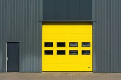 a yellow garage door is open in front of a gray building with two black doors