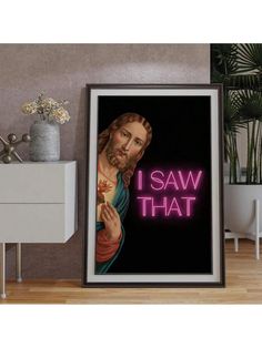 a framed poster with the words i saw that in neon pink on it next to a white cabinet