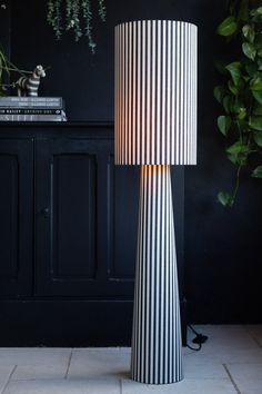 a black and white lamp sitting on top of a table next to a potted plant