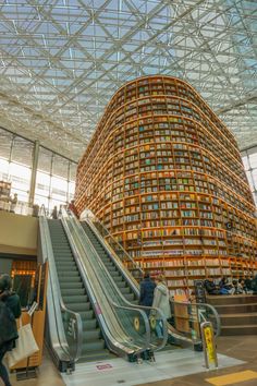 an escalator in the middle of a library filled with lots of books and people