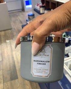 a hand is holding a jar of marshmallow fire cider candle in a store