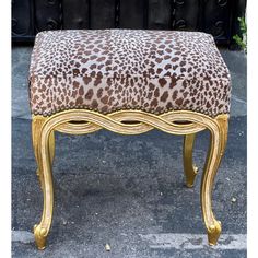 a leopard print upholstered bench with gold trimmings and an ornate foot rest