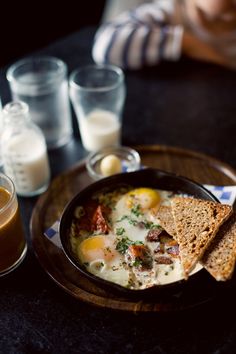 an omelet with toast and eggs in a bowl on a table next to glasses of milk