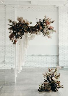 an arrangement of flowers and greenery on display in front of a white brick wall