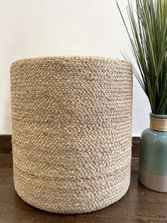 a large round woven basket next to a small potted plant on a wooden table