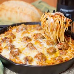 a skillet filled with spaghetti and meatballs being lifted from the casserole