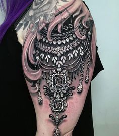 the back of a woman's shoulder with an intricate tattoo design on her arm