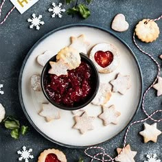 a plate with cookies and jam on it next to some christmas decorations, stars and snowflakes