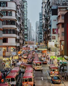 there are many buses that are driving down the street in this city, and it is very crowded