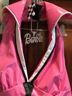 a pink rain coat with the word barbie on it and a black bow tie hanging