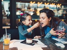 mother and daughter eating cake together in a restaurant stock photo