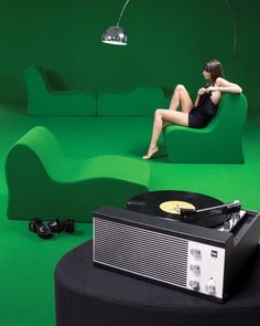 a woman sitting on a green couch next to a record player