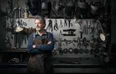 a man standing in front of a wall filled with lots of tools and wrenches