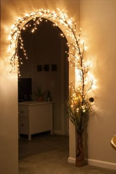 a vase with flowers and lights on the side of a wall next to a mirror