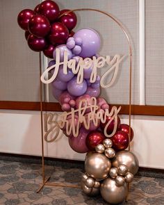 a happy birthday sign surrounded by balloons and other holiday decorations on a stand in front of a door