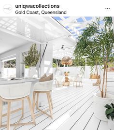 an outdoor dining area with white furniture and potted plants