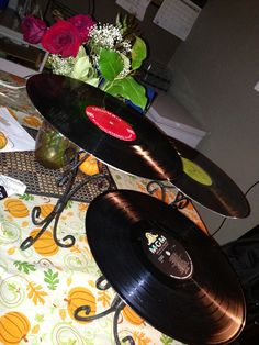 two records are stacked on top of each other near a vase with flowers in it