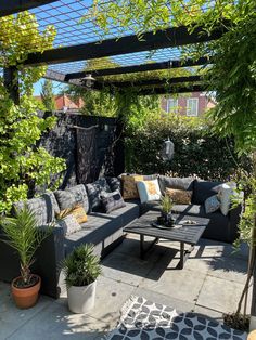 an outdoor living area with couches, tables and potted plants