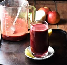 a pitcher of juice next to a plate with fruit on it